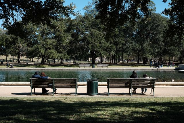 Visitors enjoy a relaxing afternoon by the pond in a Houston city park