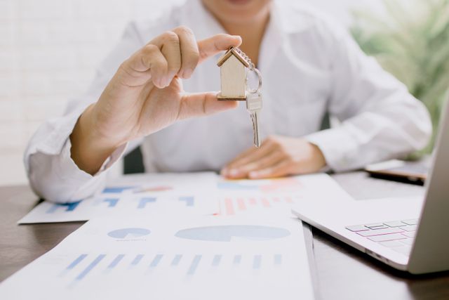 professional presenting a house model with keys