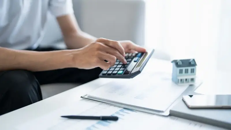 A person calculating the break even point between reducing rent or accepting a longer vacancy